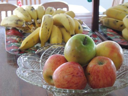 a glass bowl of apples and bananas on a table at Hotel Beira Rio in Brusque