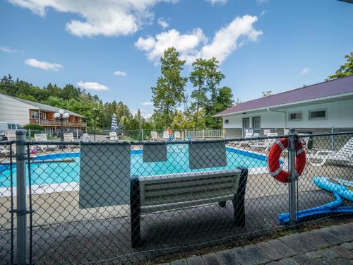 a fence with a park bench in front of a pool at Lake 'N Pines Motel in Cooperstown