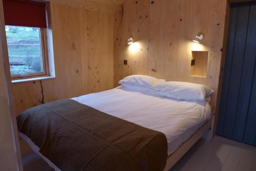 1 dormitorio con 1 cama en una pared de madera en The Tin Church en Port na Long