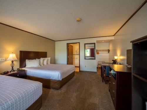 a hotel room with two beds and a flat screen tv at Lake 'N Pines Motel in Cooperstown