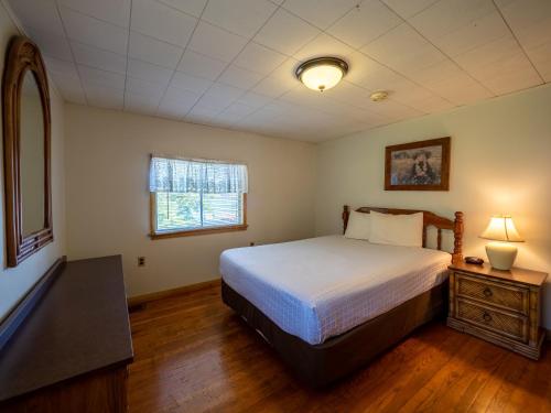 a bedroom with a bed and a window at Lake 'N Pines Motel in Cooperstown