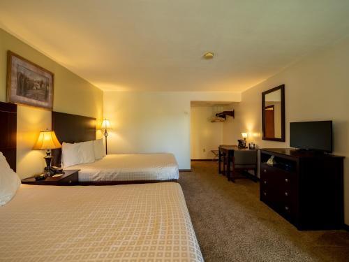 a hotel room with two beds and a desk and a television at Lake 'N Pines Motel in Cooperstown