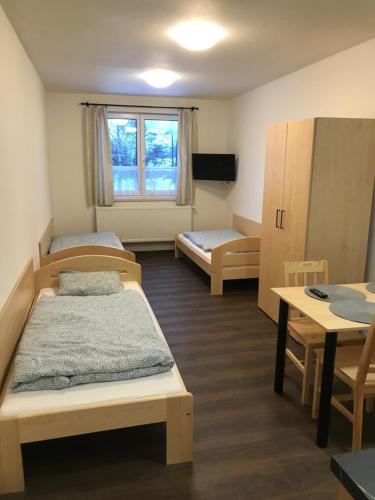 Habitación con 3 camas, mesa y escritorio. en Penzion Alvarez, en Ostrov nad Oslavou