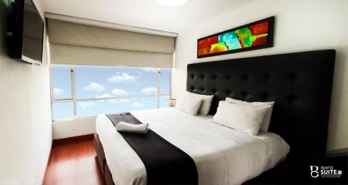 a bedroom with a large bed with a large window at Apartasuites Plaza Modelia in Bogotá