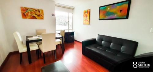 sala de estar con sofá de cuero negro y mesa en Apartasuites Plaza Modelia, en Bogotá