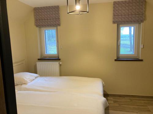 a bedroom with two white beds and two windows at Au Bois de Rosée in Florennes