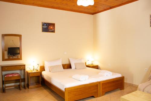 ein Schlafzimmer mit einem Bett mit weißen Laken und einem Spiegel in der Unterkunft Nanos Studios in Parga