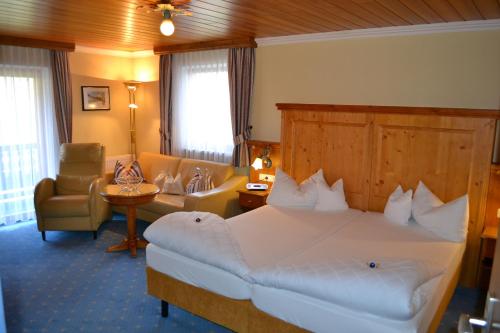 una habitación de hotel con una cama grande y una silla en Hotel Alpenresi en Ramsau