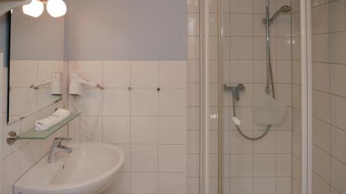 ein weißes Bad mit einer Dusche und einem Waschbecken in der Unterkunft Haus Alte Bäckerei Deichgraf in Born