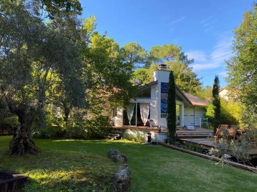 a house with a garden and a yard with trees at L'Esprit d'O in Lacanau
