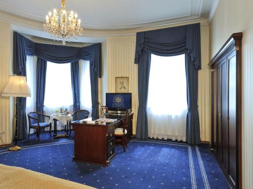 a hotel room with a desk and a table and windows at Hotel Ambassador in Vienna
