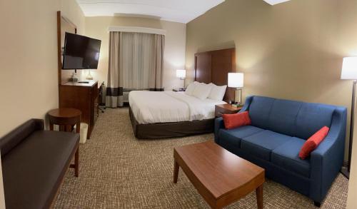 a hotel room with a bed and a blue couch at Wingate by Wyndham Pittsburgh West Mifflin in West Mifflin