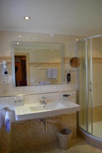 a bathroom with a sink and a mirror and a shower at Hotel Alpenresi in Ramsau
