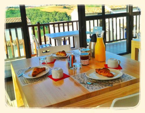 a table with two plates of croissants and orange juice at Résidence L'Oustal Del Carlat in Carla-Bayle