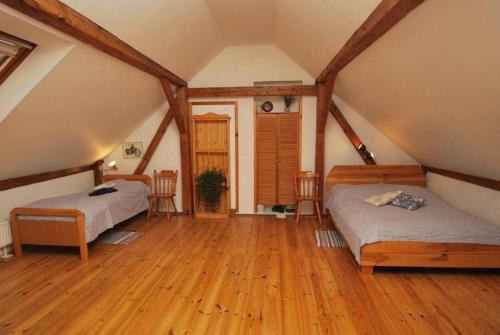 een slaapkamer op zolder met 2 bedden en houten vloeren bij The Bohemian Farmhouse 