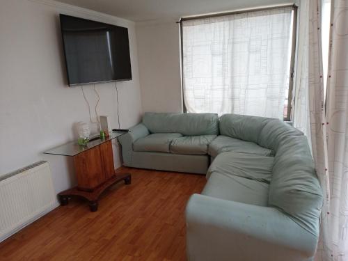 a living room with a couch and a television at Departamento Impecable in Santiago