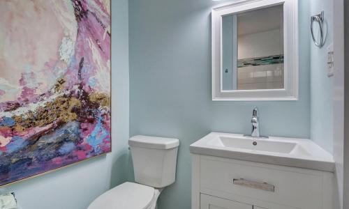 a bathroom with a toilet and a sink and a painting at Loggerhead Inn and Suites in Surf City