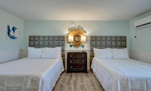 two beds sitting next to each other in a bedroom at Loggerhead Inn and Suites in Surf City