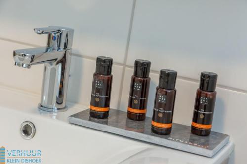 four bottles of essential oils sitting on a bathroom sink at Appartement - Kaapduinseweg 13 Dishoek 13A Luxe 4 personen in Dishoek