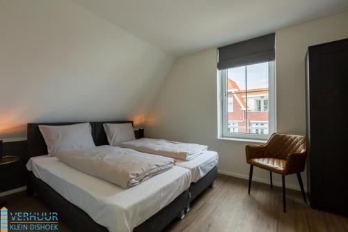 a bedroom with a bed and a chair and a window at Appartement - Kaapduinseweg 13 Dishoek 13D Luxe 6 personen in Dishoek