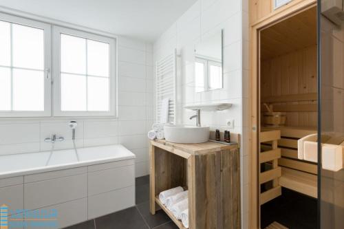 a white bathroom with a sink and a tub at Appartement - Kaapduinseweg 13 Dishoek 13D Luxe 6 personen in Dishoek