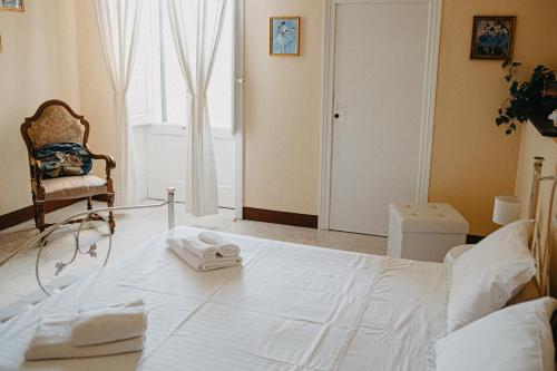 un letto bianco in una stanza con una sedia e una finestra di Piazza Argento a Lecce