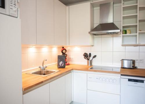 een keuken met witte kasten en een wastafel bij Ferienwohnung - Am Roten Kreuz 11 in Winterberg