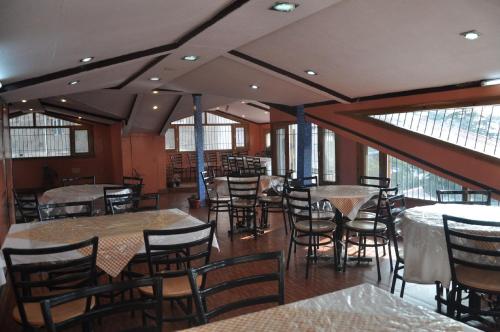 a dining room with tables and chairs and windows at Hotel Prestige in Shimla