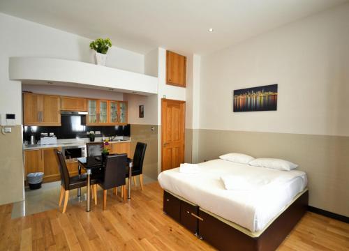 a bedroom with a bed and a table and a kitchen at Hyde Park Apartments in London