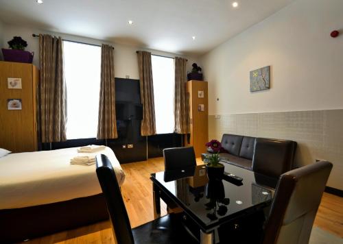 a hotel room with a bed and a desk and chairs at Hyde Park Apartments in London