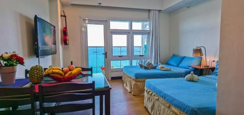 a room with two beds and a table with a bowl of fruit at OceanFront at Arterra, fast WiFi, NFlix, kitchen -C in Mactan