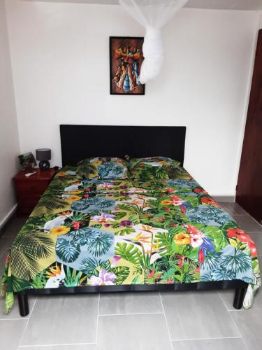 a bed with a colorful comforter on it in a bedroom at Gîte Acélie in Morne-à-lʼEau