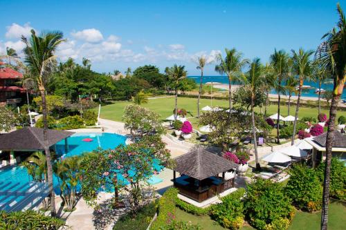 
a beach area with a pool, lawn chairs, and patio furniture at Holiday Inn Resort Baruna Bali, an IHG Hotel - CHSE Certified in Kuta

