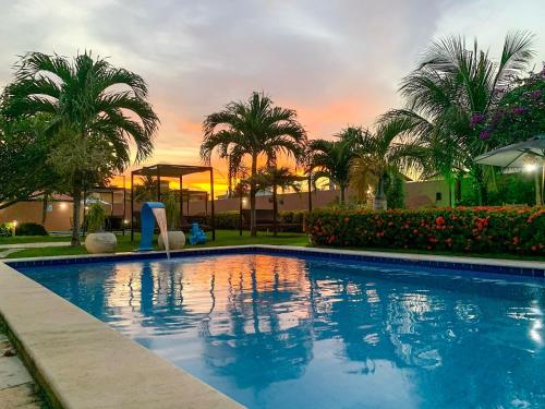 una piscina con palmeras y una puesta de sol en La Dolce Vita Flat & Pousada en Praia do Frances