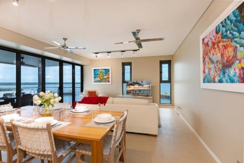 a dining room and living room with a table and chairs at Darwin Waterfront Luxury Suites in Darwin