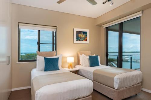 two beds in a room with windows at Darwin Waterfront Luxury Suites in Darwin