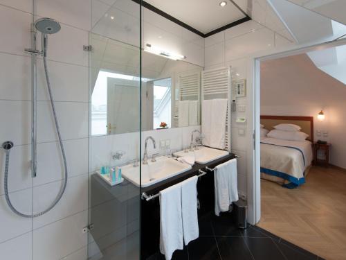 un bagno con doccia, lavandino e letto di Hotel Ambassador a Vienna