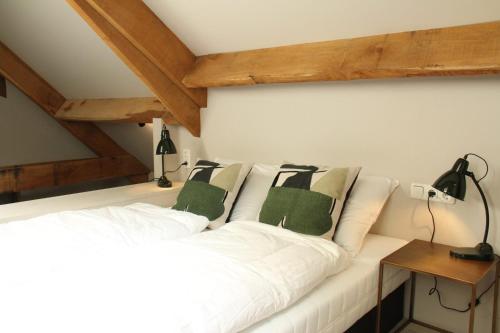 een slaapkamer met een wit bed met groene kussens bij Vlindervallei 2p in Ermelo
