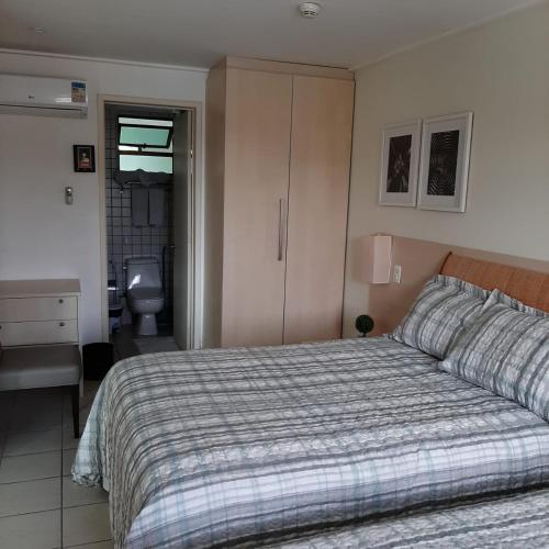 a bedroom with a bed and a desk and a bathroom at Beach Class Muro Alto - Dele's Flat in Porto De Galinhas