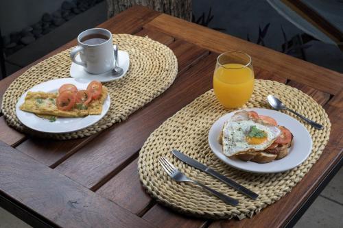 a table with two plates of breakfast food and a glass of orange juice at AGAM Hotel Boutique Bacalar - Adults Only in Bacalar