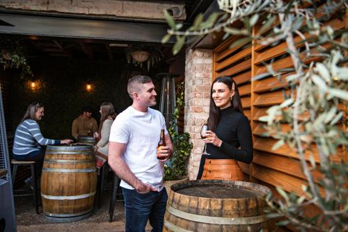 un hombre y una mujer parados junto a barriles de vino en The Woolpack Hotel, en Mudgee