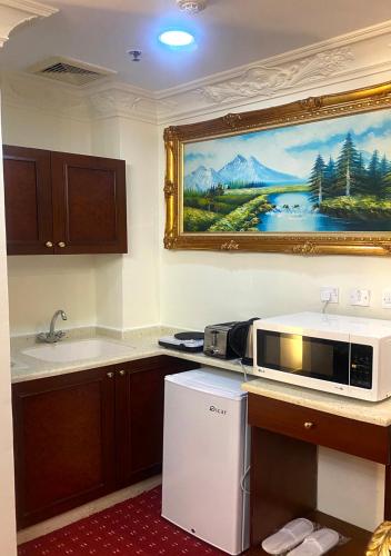 a kitchen with a microwave and a painting on the wall at Majestic Hotel in Doha