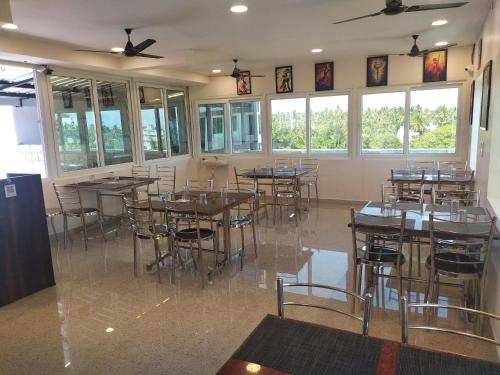 - une salle à manger avec des tables, des chaises et des fenêtres dans l'établissement Hotel Rani and Rani Residency, à Pondichéry