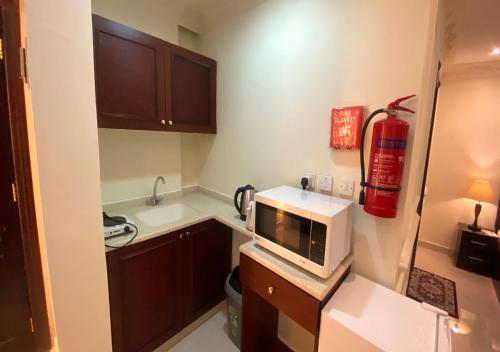 a small kitchen with a microwave on a counter at Majestic Hotel in Doha