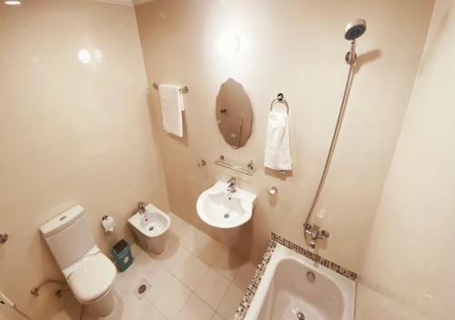 a bathroom with a toilet and a sink and a urinal at Majestic Hotel in Doha