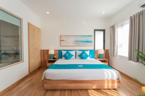 a bedroom with a large bed with blue pillows at Rivera Tuy Hòa Hotel in Tuy Hoa