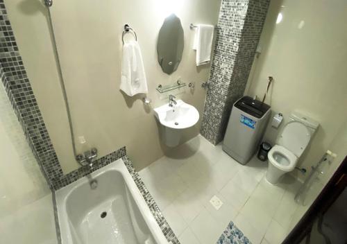 a bathroom with a tub and a sink and a toilet at Majestic Hotel in Doha