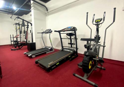 a gym with several tread machines in a room at Majestic Hotel in Doha