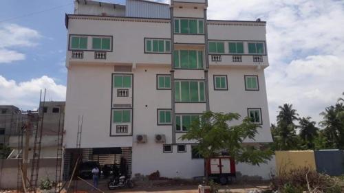 un edificio blanco alto con ventanas verdes. en Hotel Rani and Rani Residency, en Pondicherry