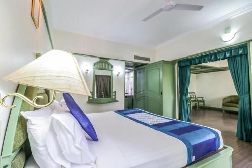 a bedroom with a large bed with blue and green curtains at Fort Gate Hotels & Resorts in Trichūr